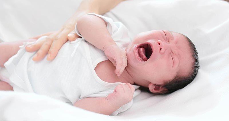Em bé sơ sinh đang uống sữa blackmore số 1 hộp nhỏ từ bình sữa, trông vui vẻ và khỏe mạnh, mẹ âu yếm nhìn con